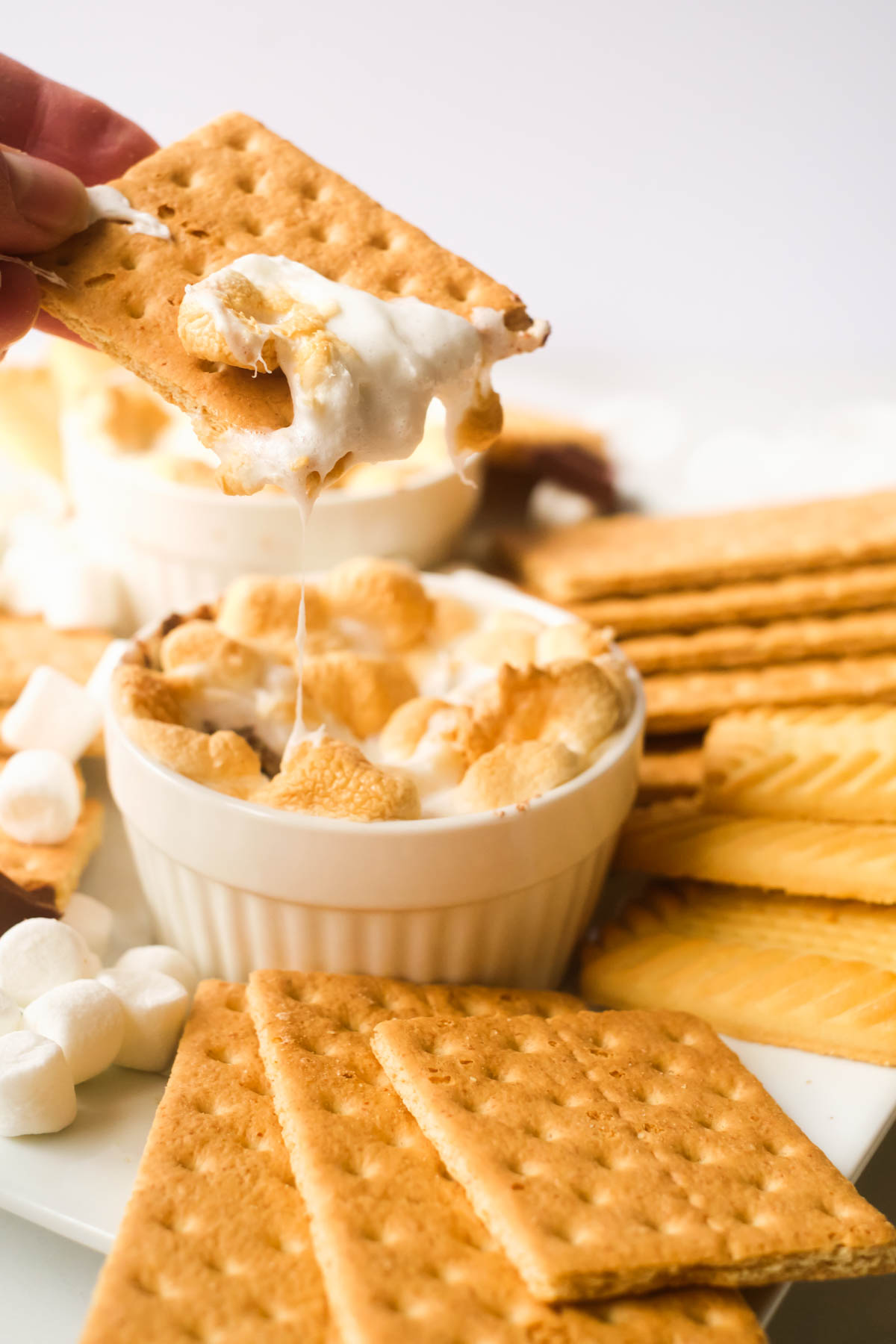 one graham cracker being dipped into the finished air fryer smores dip