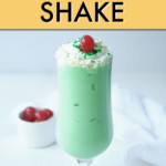 A GREEN SHAKE WITH WHIPPED CREAM AND CHERRY IN A GLASS