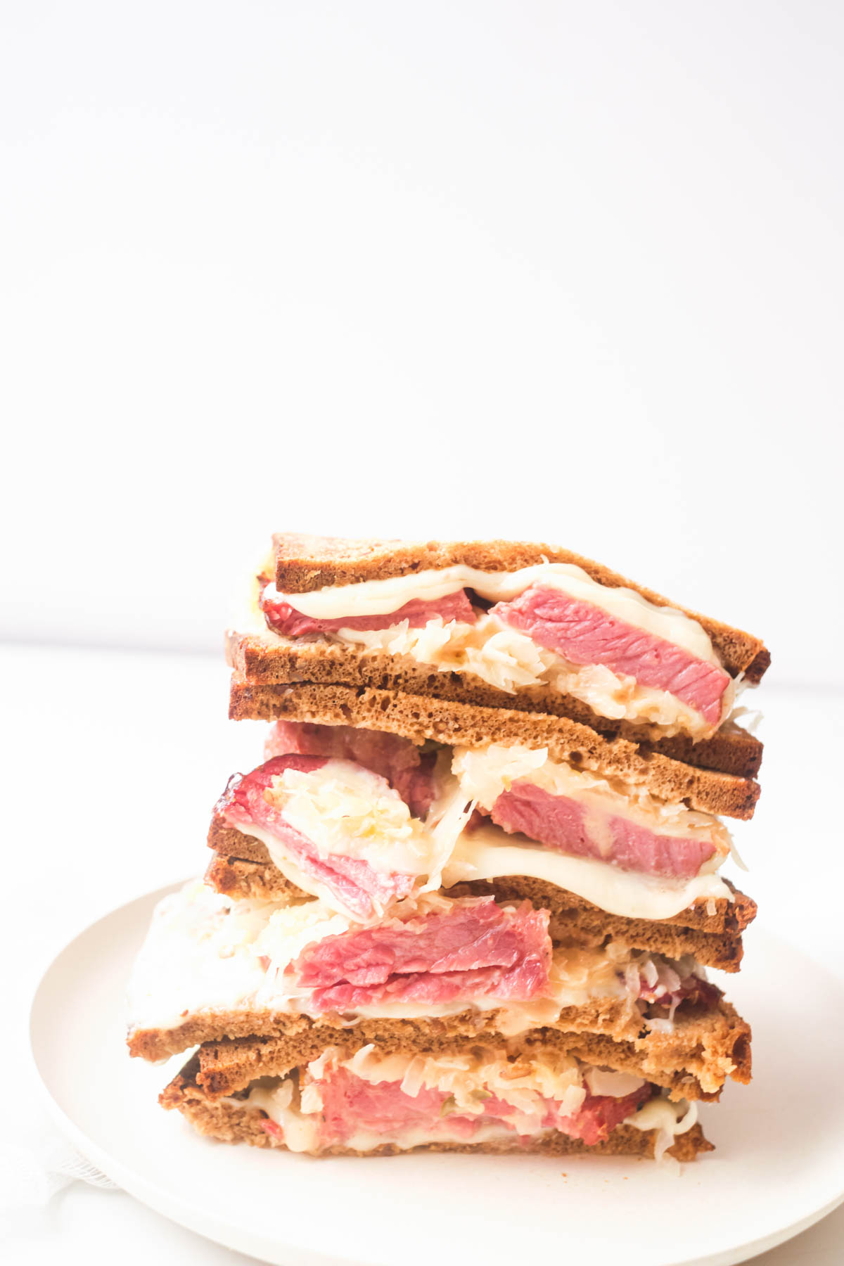 side view of the finished air fryer reuben sandwich served on a white plate