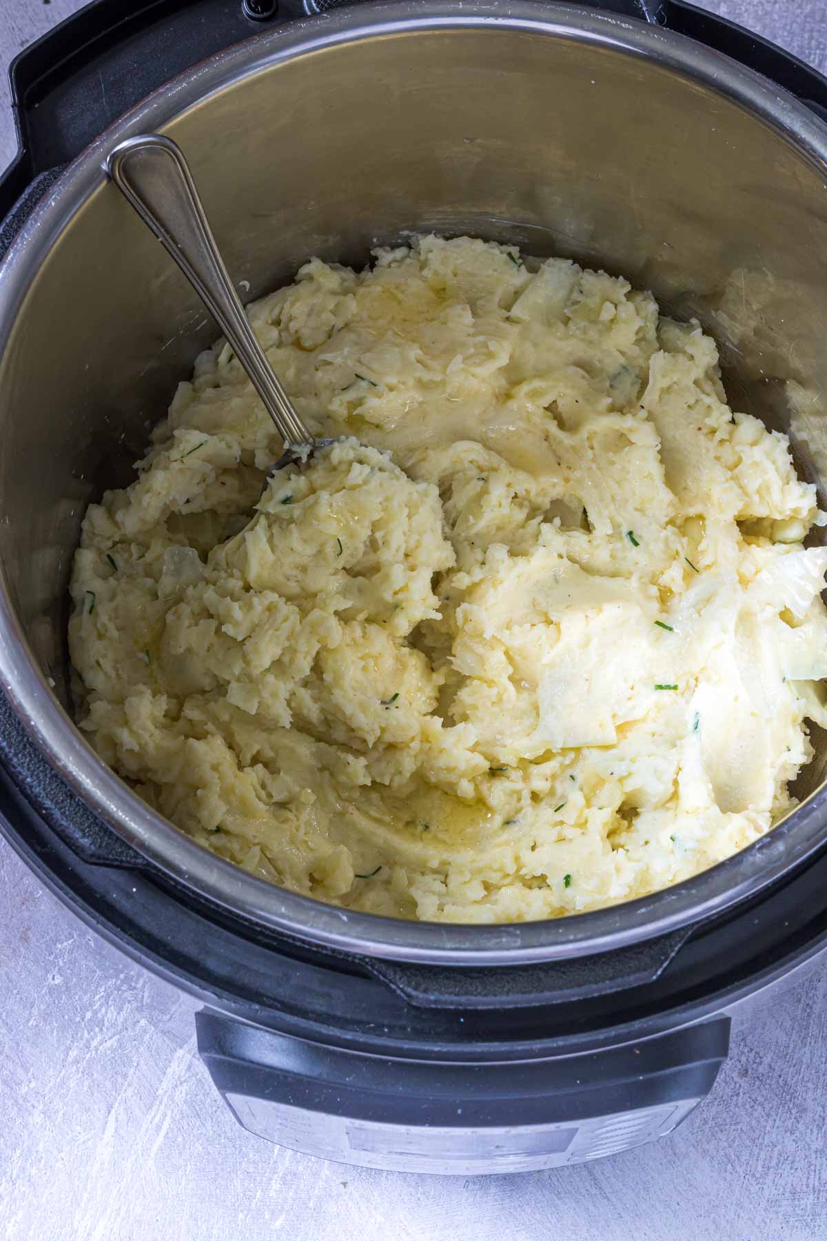 the finished instant pot colcannon inside the instant pot insert being stirred with a spoon.