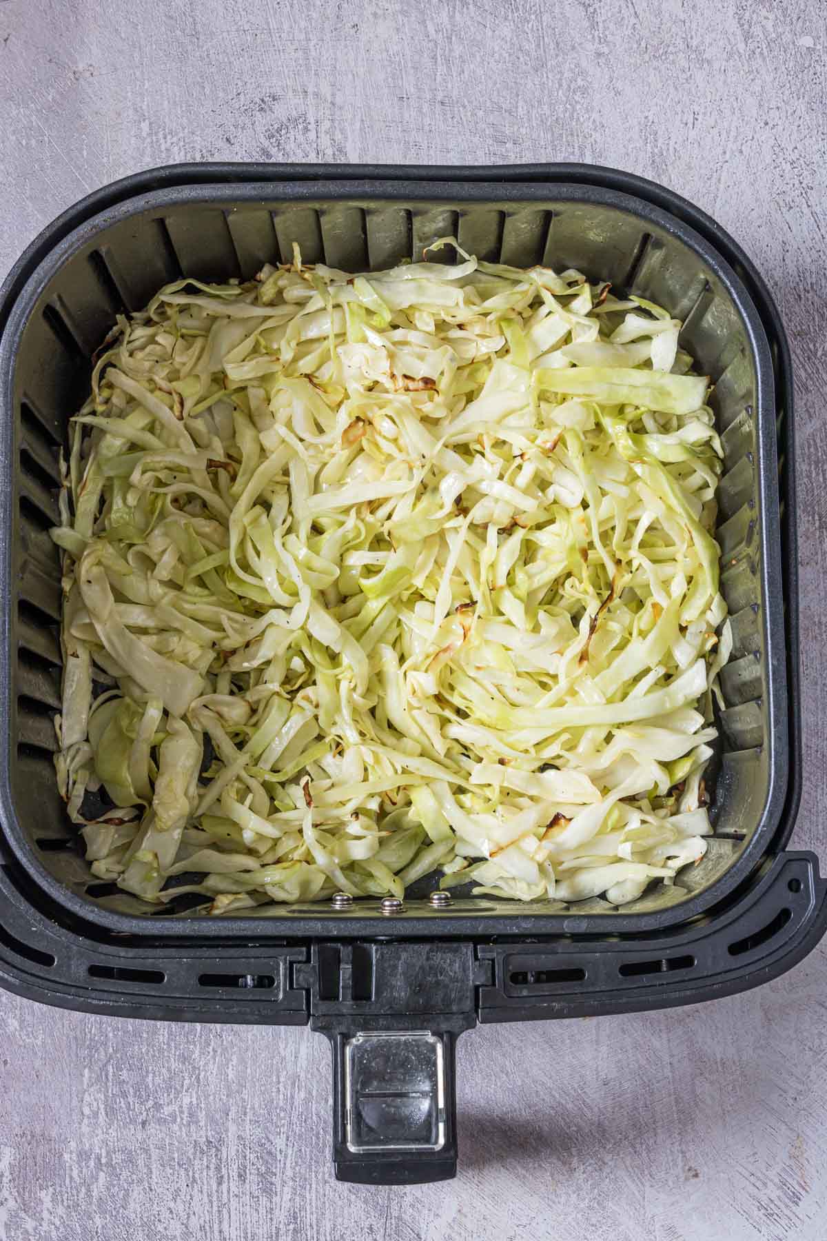 the completed air fried cabbage recipe inside the air fryer basket.