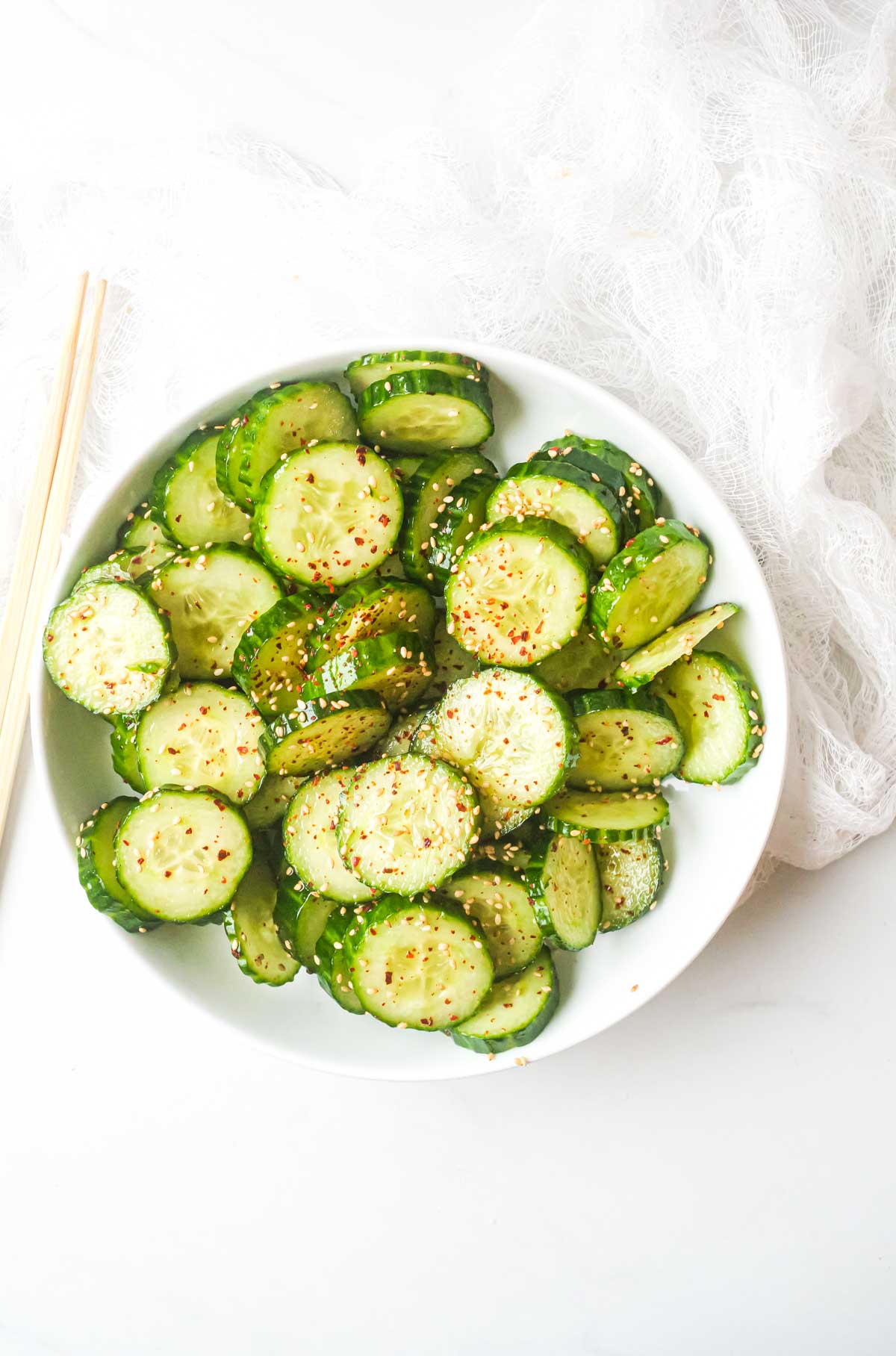 top down view of a serving of asian cucumber salad with chopsticks and cloth napkin