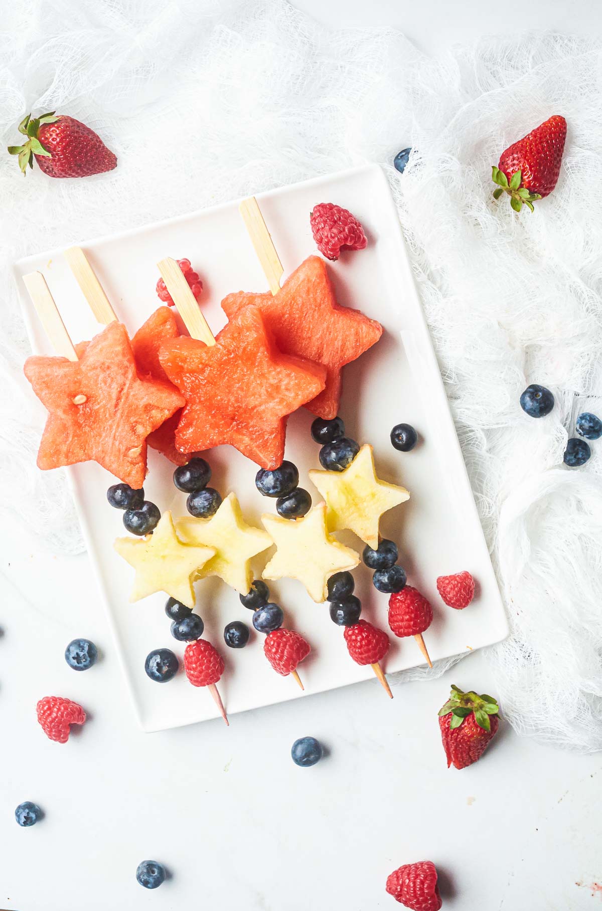 patriotic fruit skewers on. aplte with colorful berries dotted around