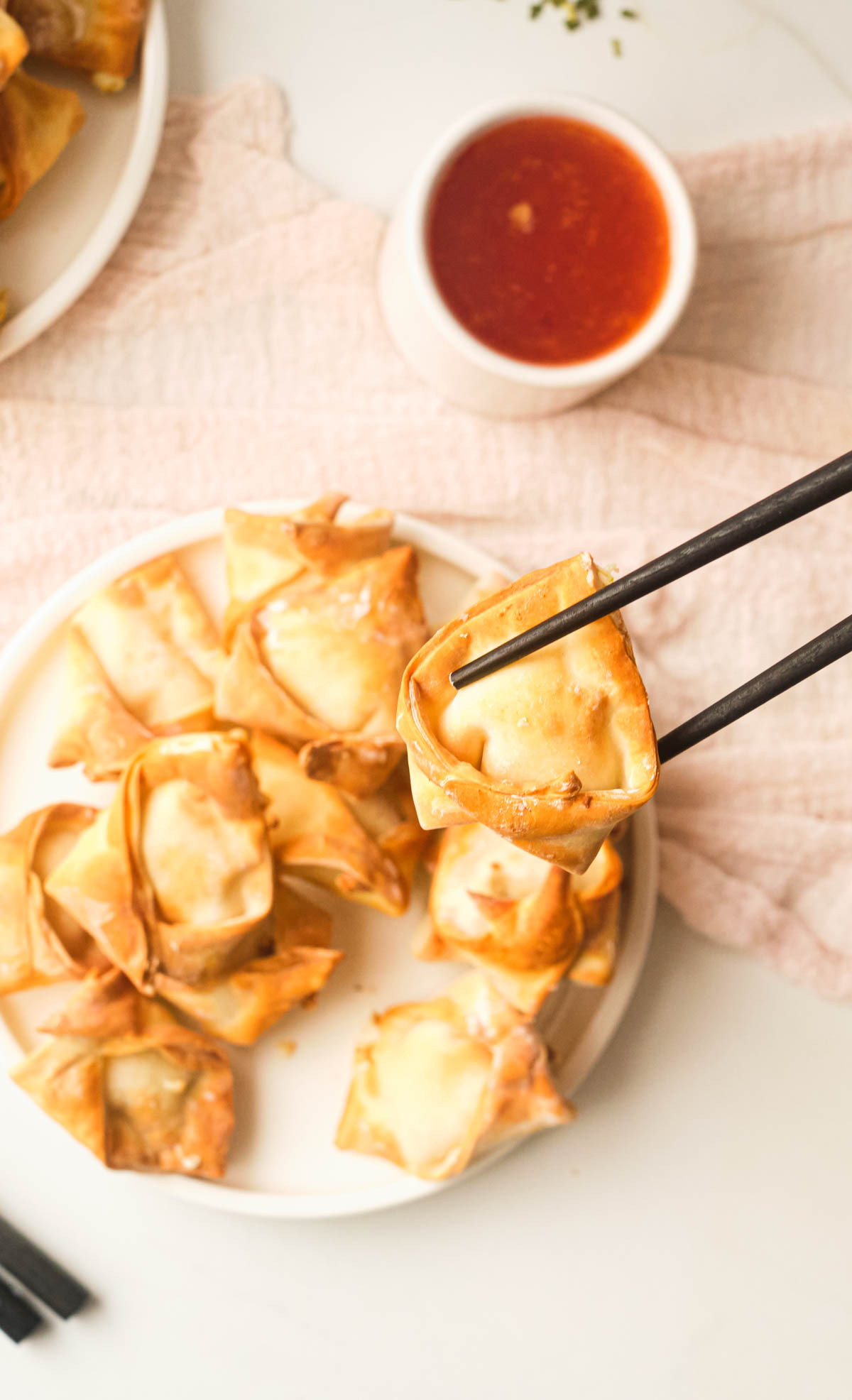top down view of a plate of air fryer wontons with chopsticks removing one