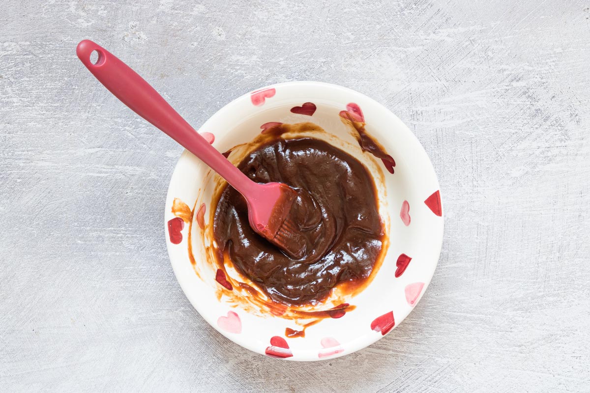 a bowl filled with bbq sauce with a brush dipped in