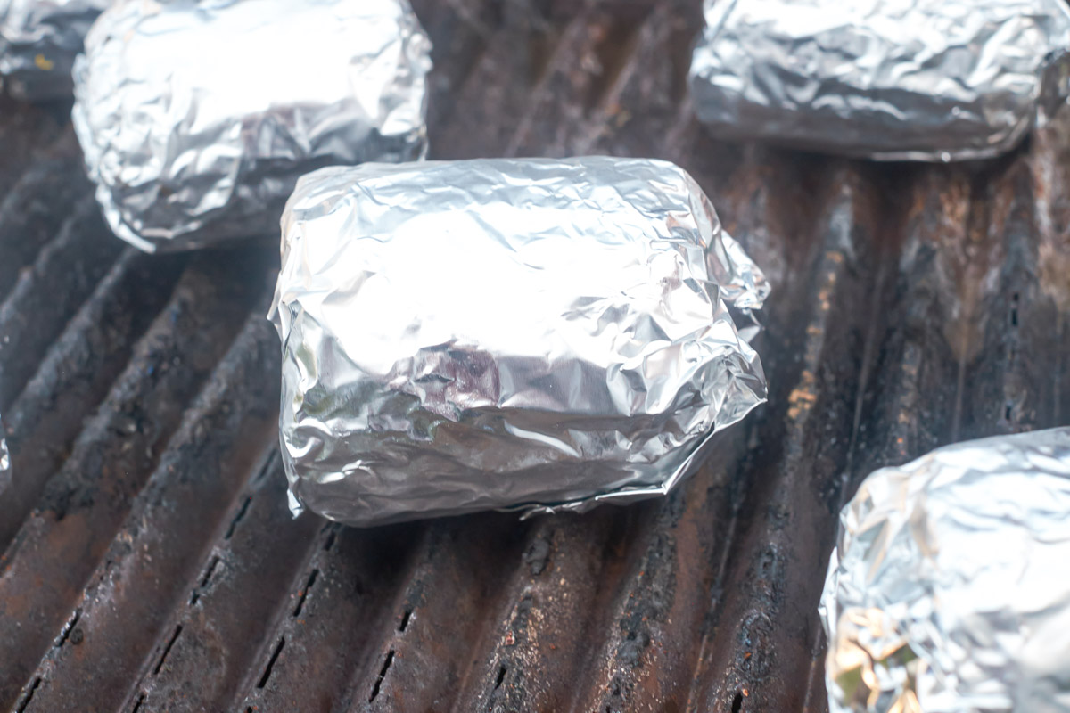Frozen corn on the cob wrapped in foil on the grill