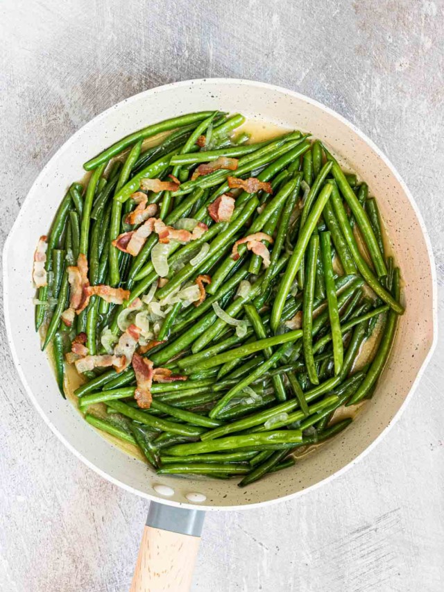 Smothered green beans in a skillet.