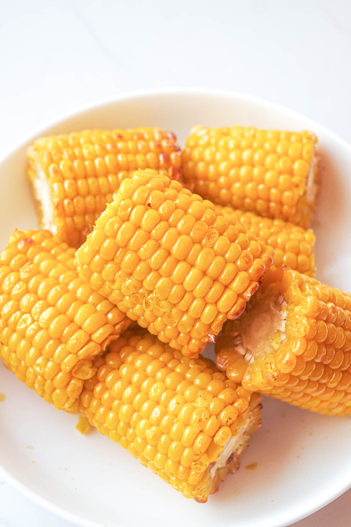 top down view of the finished frozen corn on the cob in air fryer served on a white plate