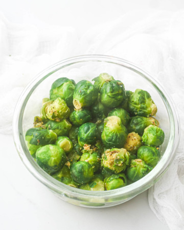 a glass bowl holding frozen brussel sprouts in how to cook frozen brussel sprouts recipe