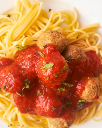 top down view of a plate of pasta topped with sauce and cooked frozen meatballs
