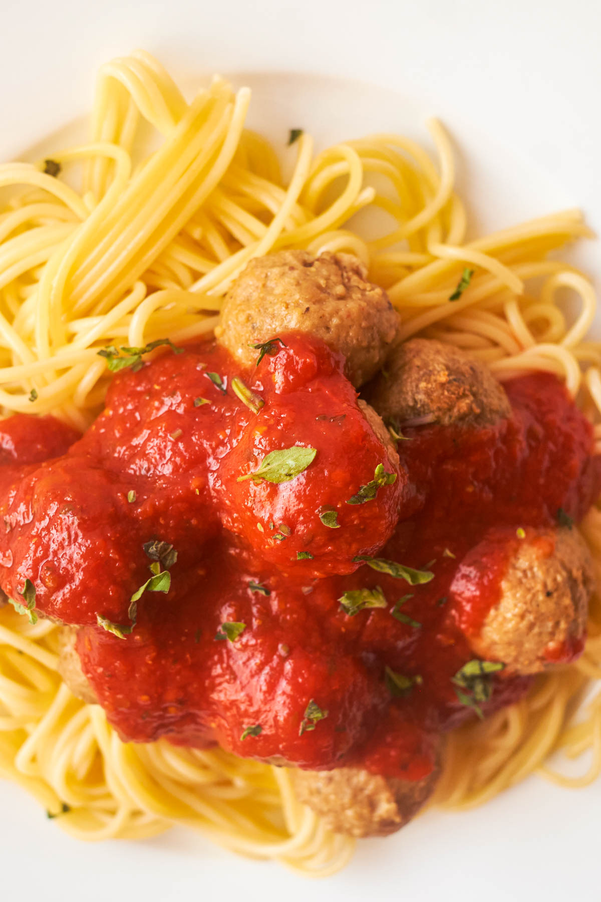 top down view of a plate of pasta topped with sauce and cooked frozen meatballs