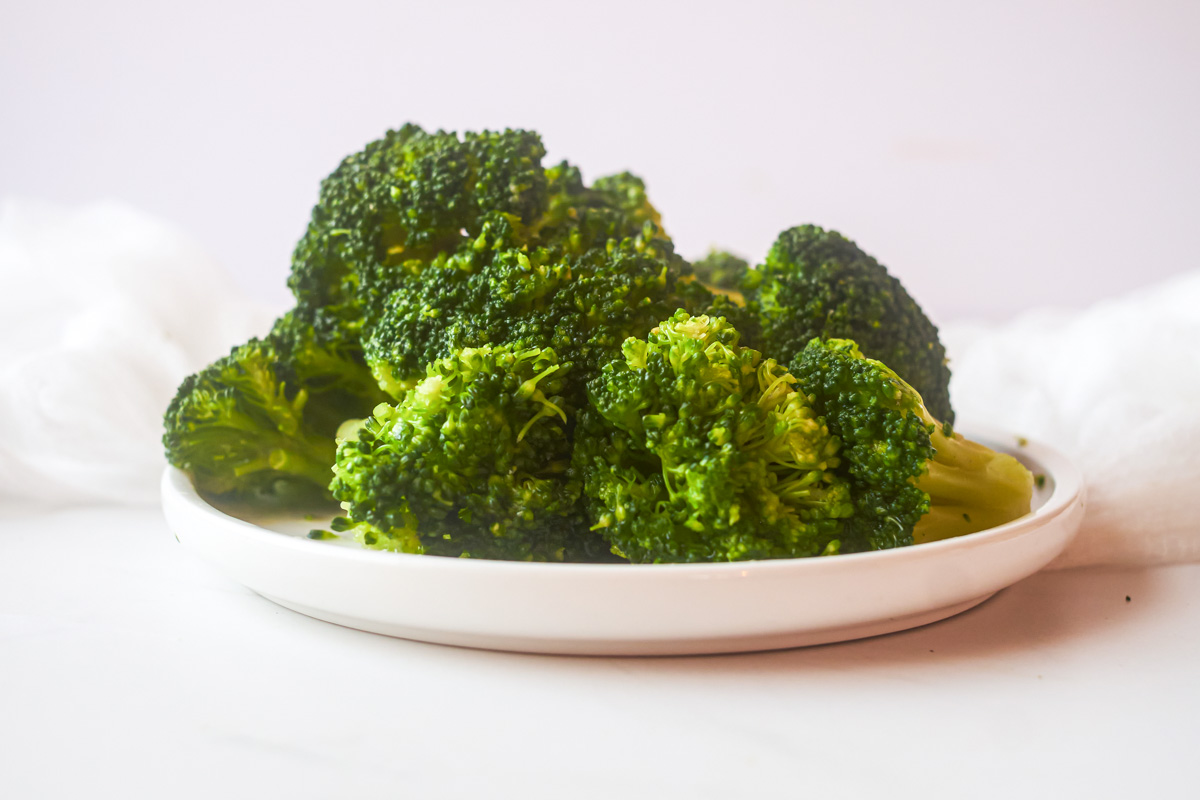 side view of a plate filled with broccoli that was steamed in microwave