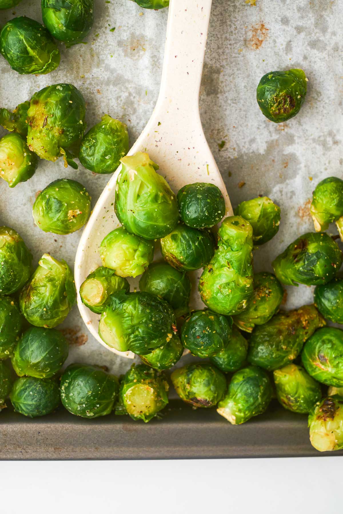 a serving spoon removing roasted frozen brussel sprouts from a baking sheet