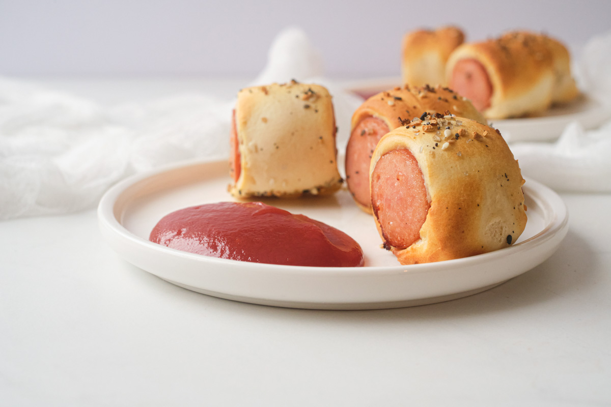 three air fryer sausage rolls served on a white plate with ketchup