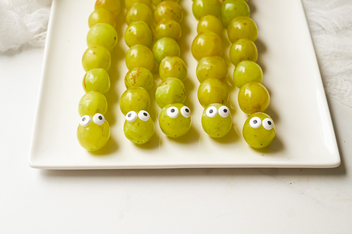 a plate full of grep grape caterpillar skewers ready to be served