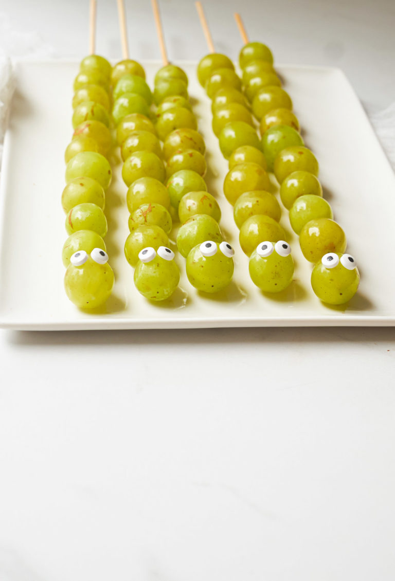 5 grape caterpillars skewers on a plate for halloween fun