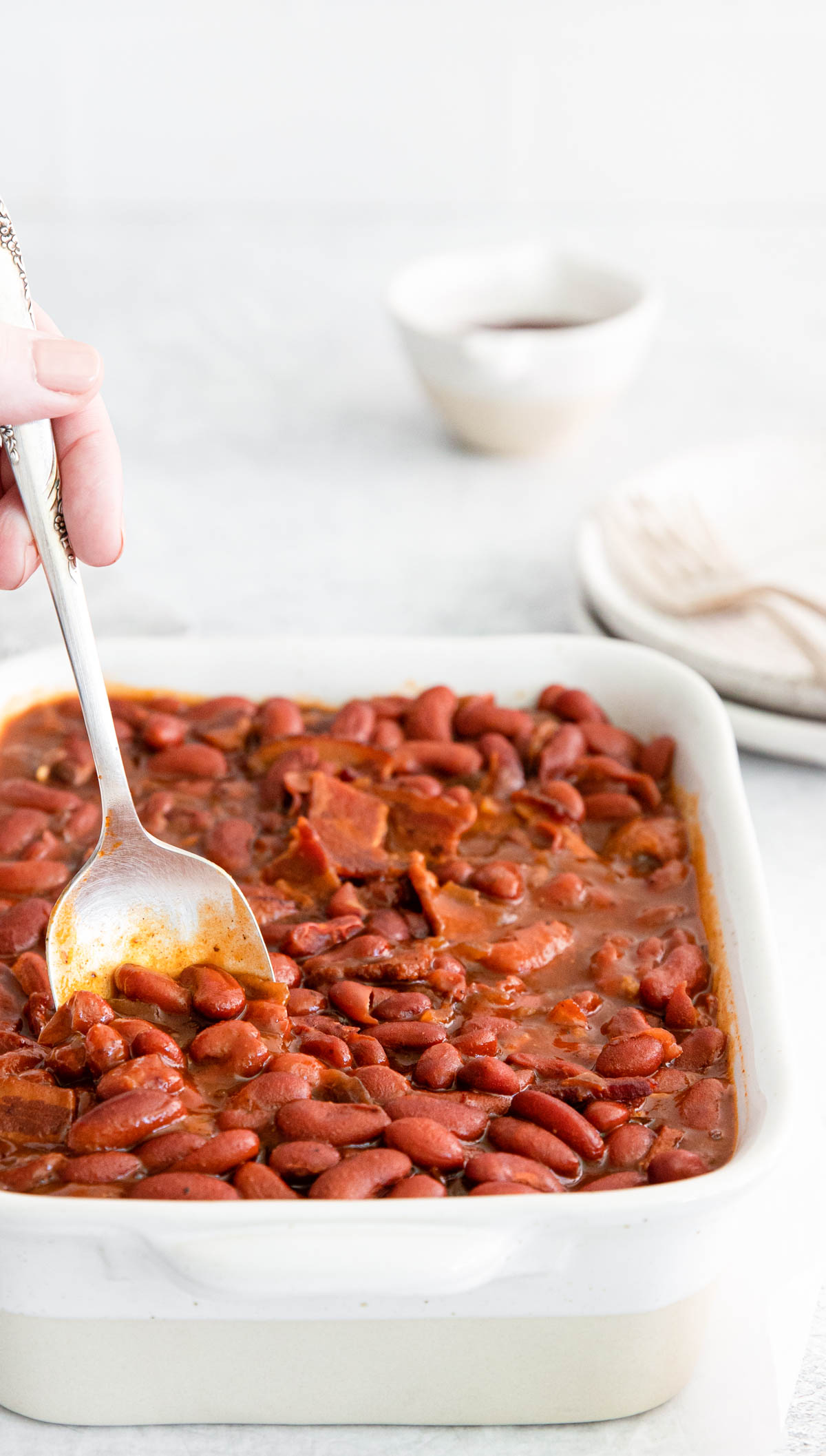 a spoon dipping into a dish filled with instant pot baked beans