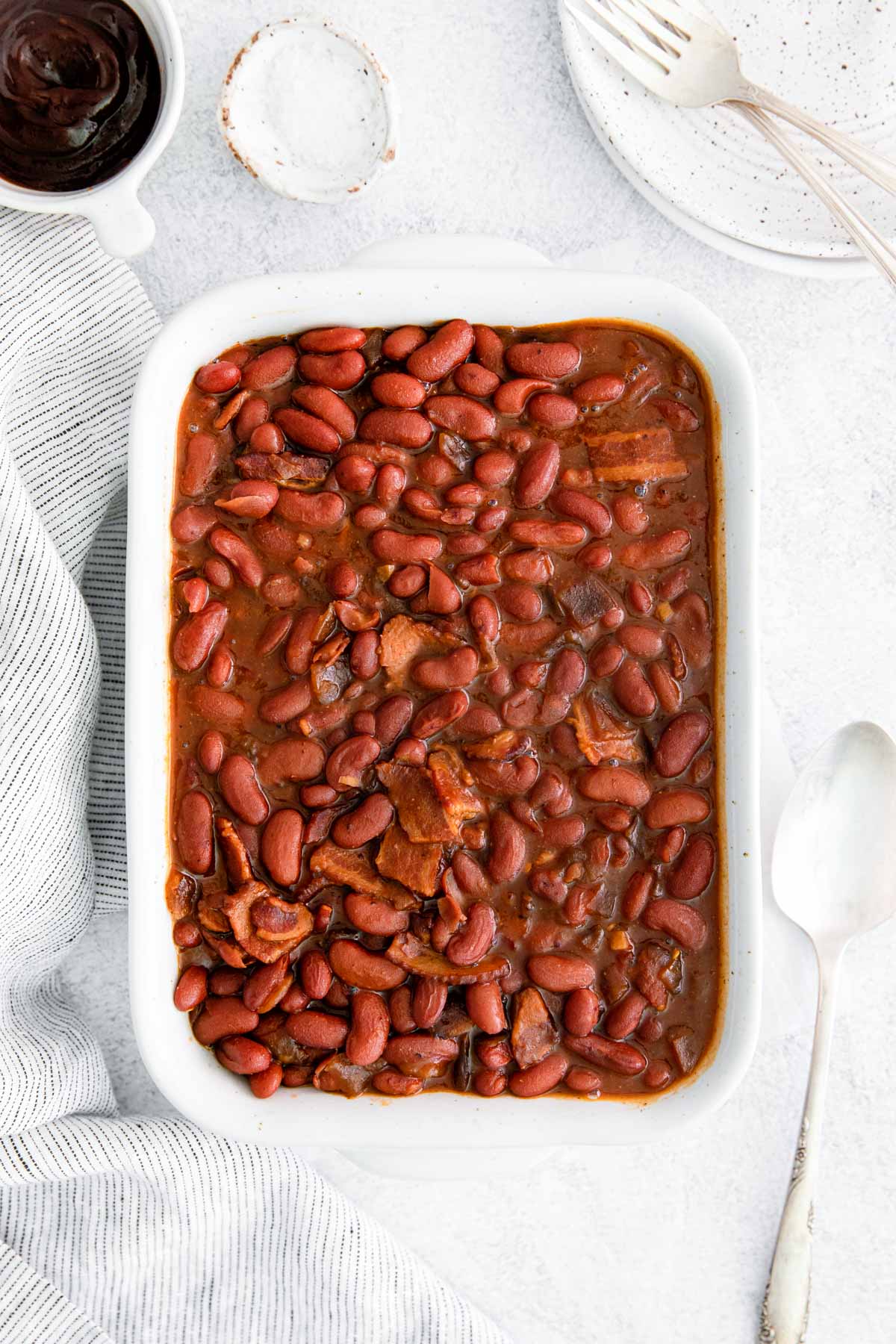 top down view of the completed instant pot baked beans served in a white dish with a serving spoon on the side