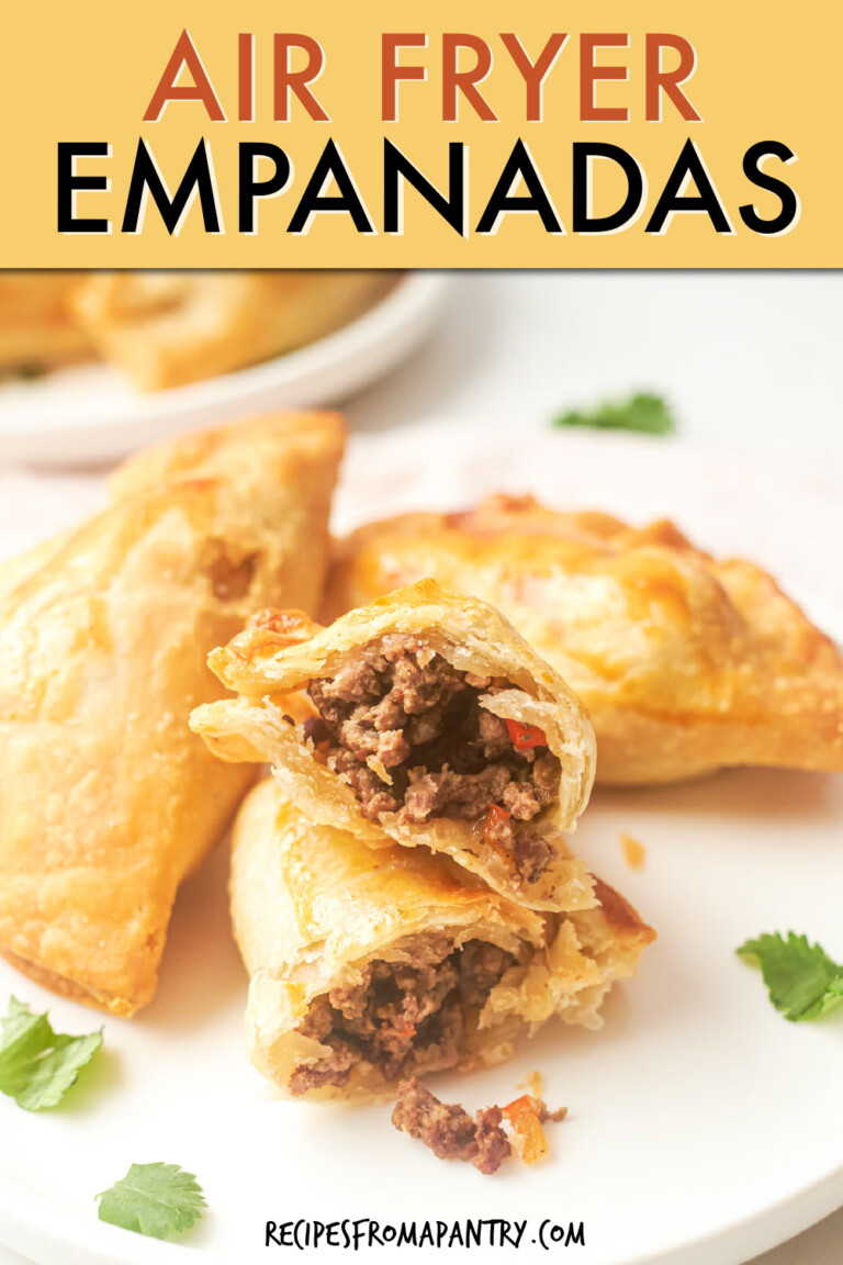 THREE EMPANADAS ON A PLATE, WITH ONE CUT IN HALF TO SHOW THE MEAT FILLING