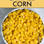 a bowl of cooked corn kernels with a spoon in it
