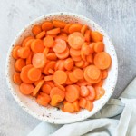 the completed how to boil carrots recipe in a serving dish with cloth napkin
