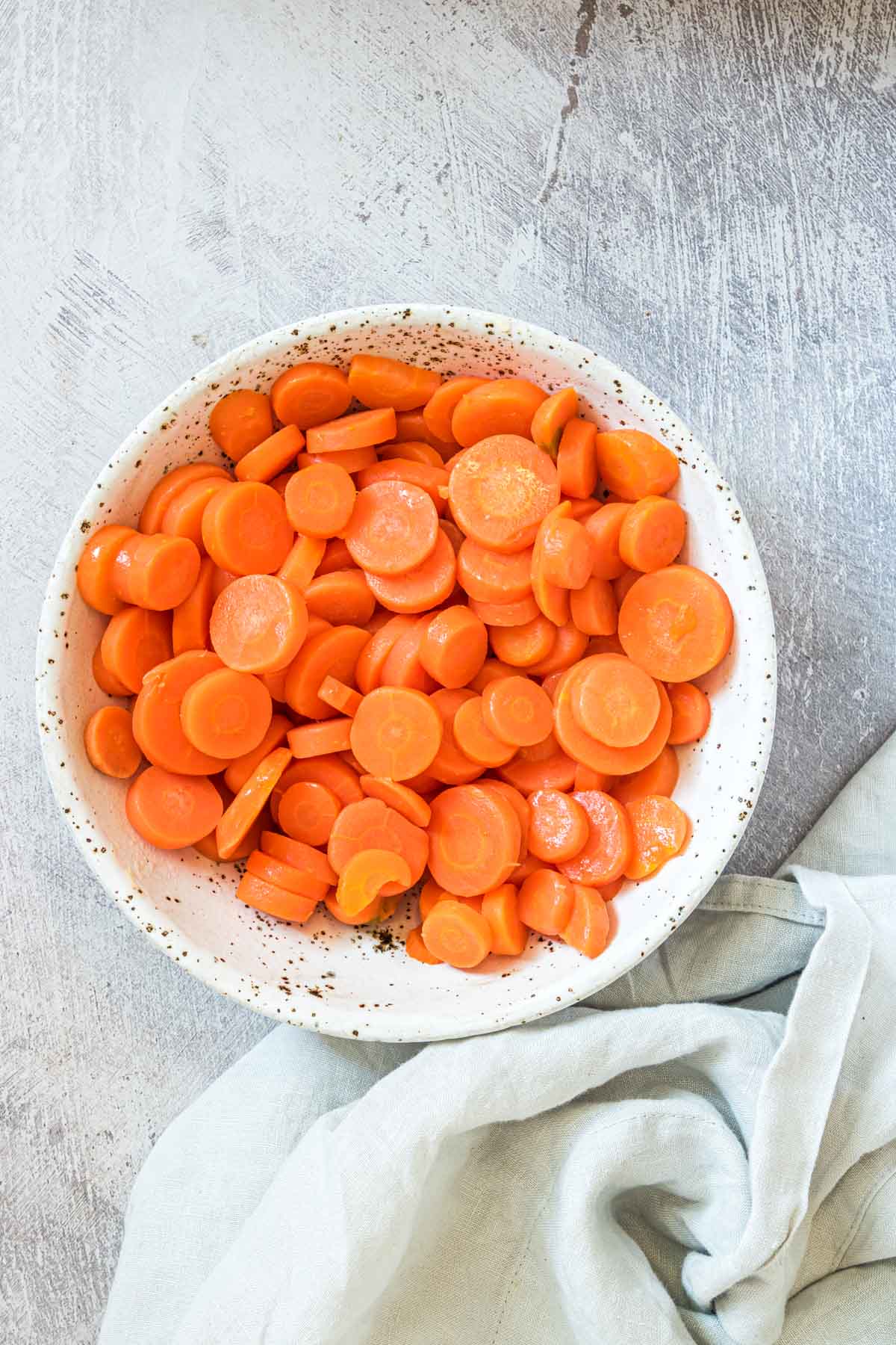 the completed how to boil carrots recipe in a serving dish with cloth napkin