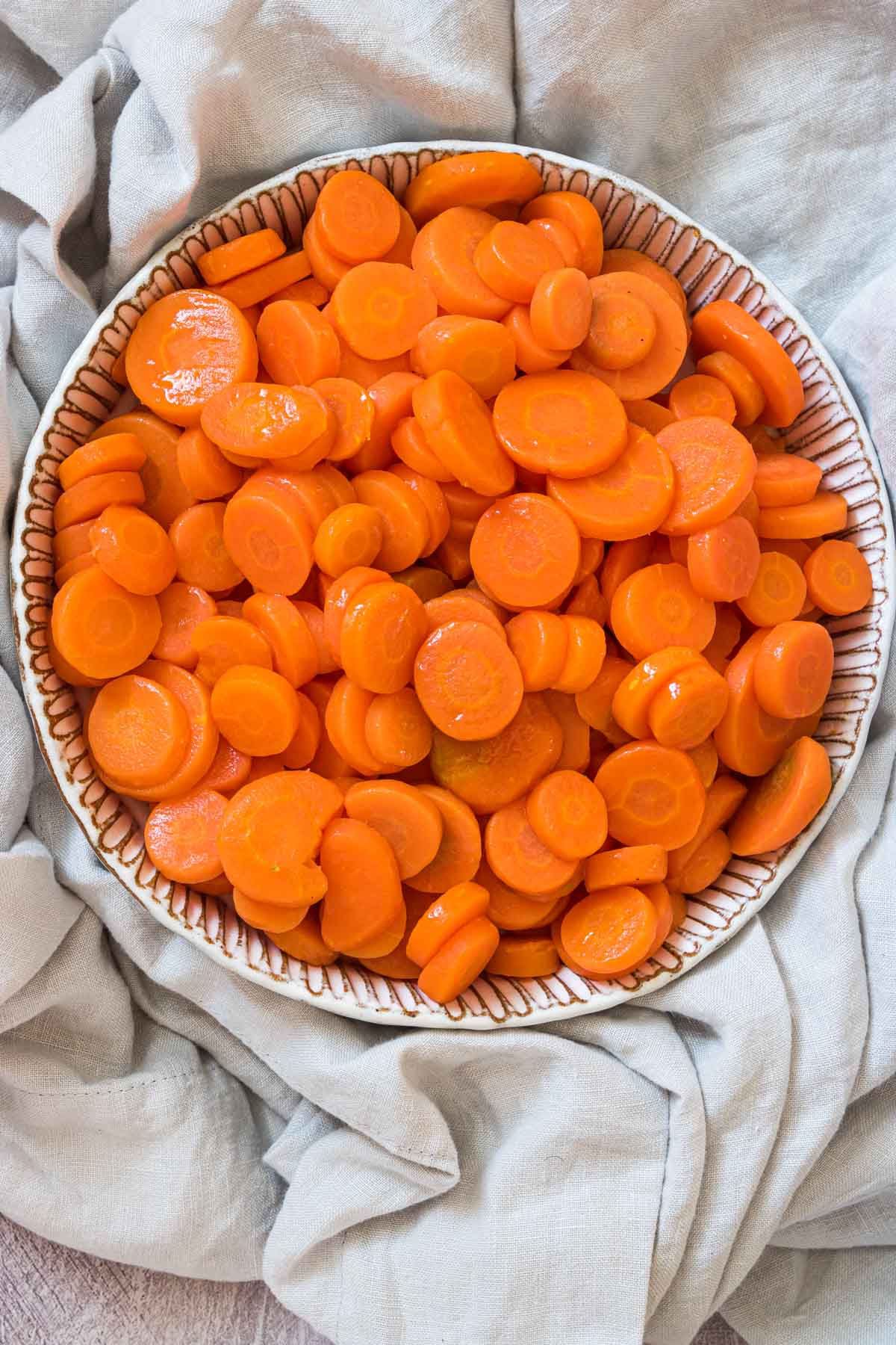 a bowl of microwave carrots served on top of a cloth dish towel