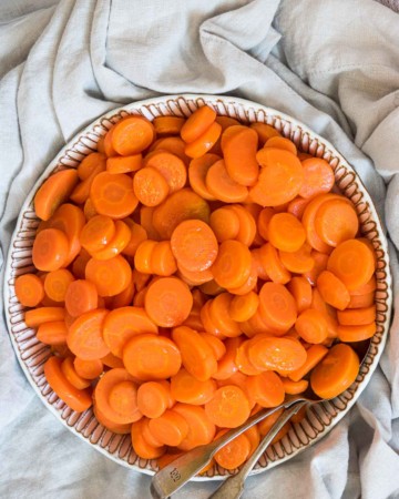 a serving bowl filled with microwave carrots and a large spoon
