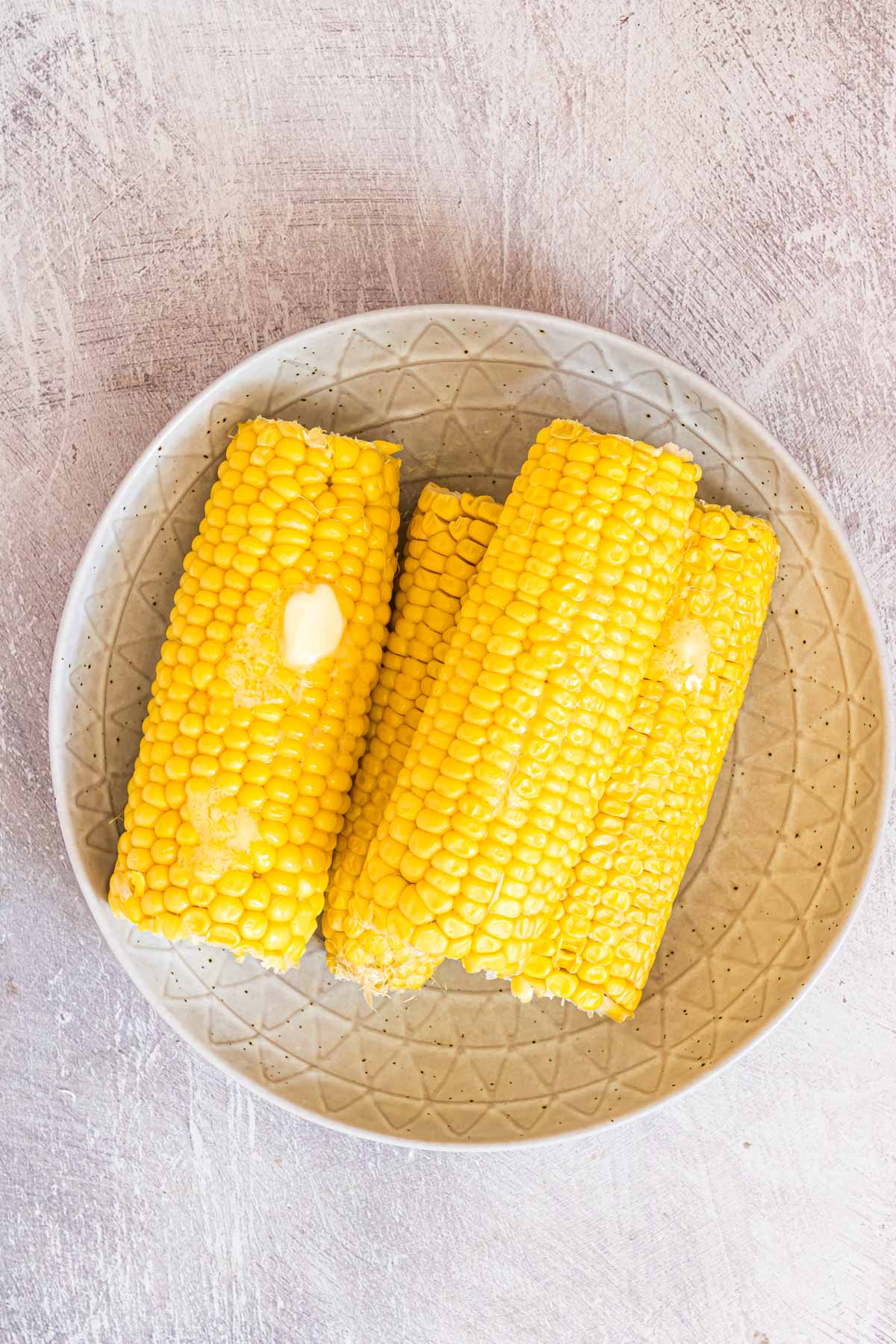 top down view of the completed microwave corn on the cob topped with butter