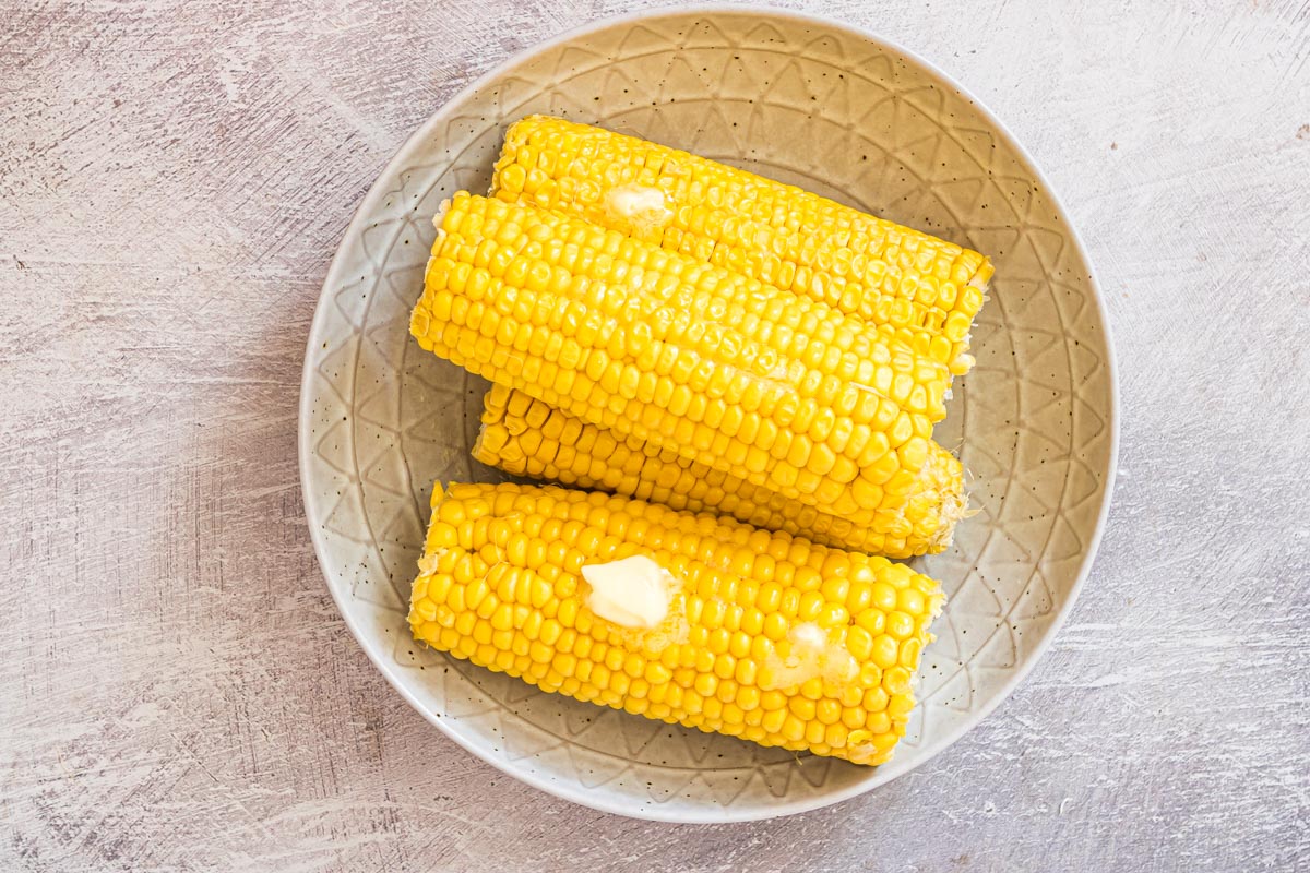 Four microwave corn cobs on the cob covered with butter