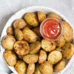 the finished air fryer baby potatoes served in a bowl with a side of dipping sauce