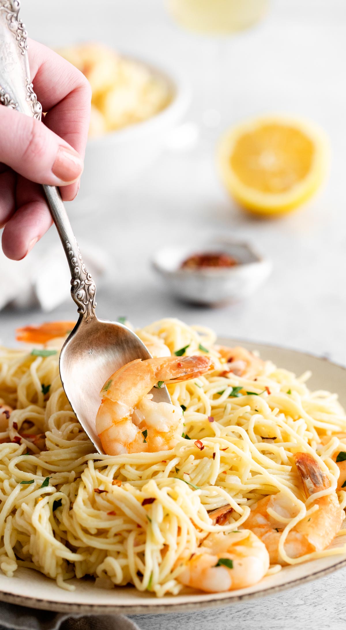 a serving spoon removing a portion of instant pot shrimp scampi from a platter