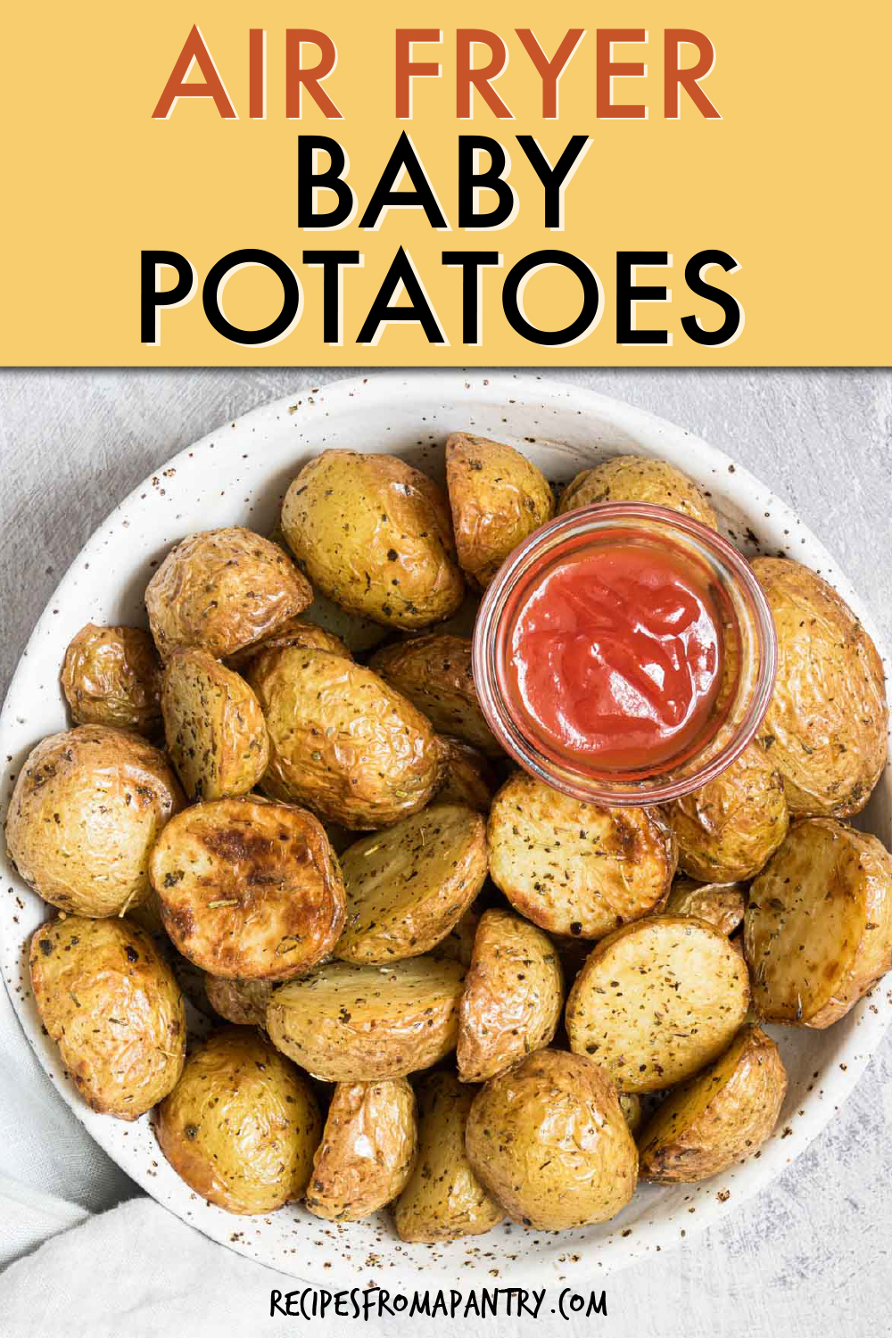 halved baby potatoes in a bowl with a dish of catsup