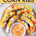corn ribs on a round plate with small dish of dipping sauce