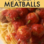 Close up of a fork going into meatballs on top of spaghetti with tomato sauce