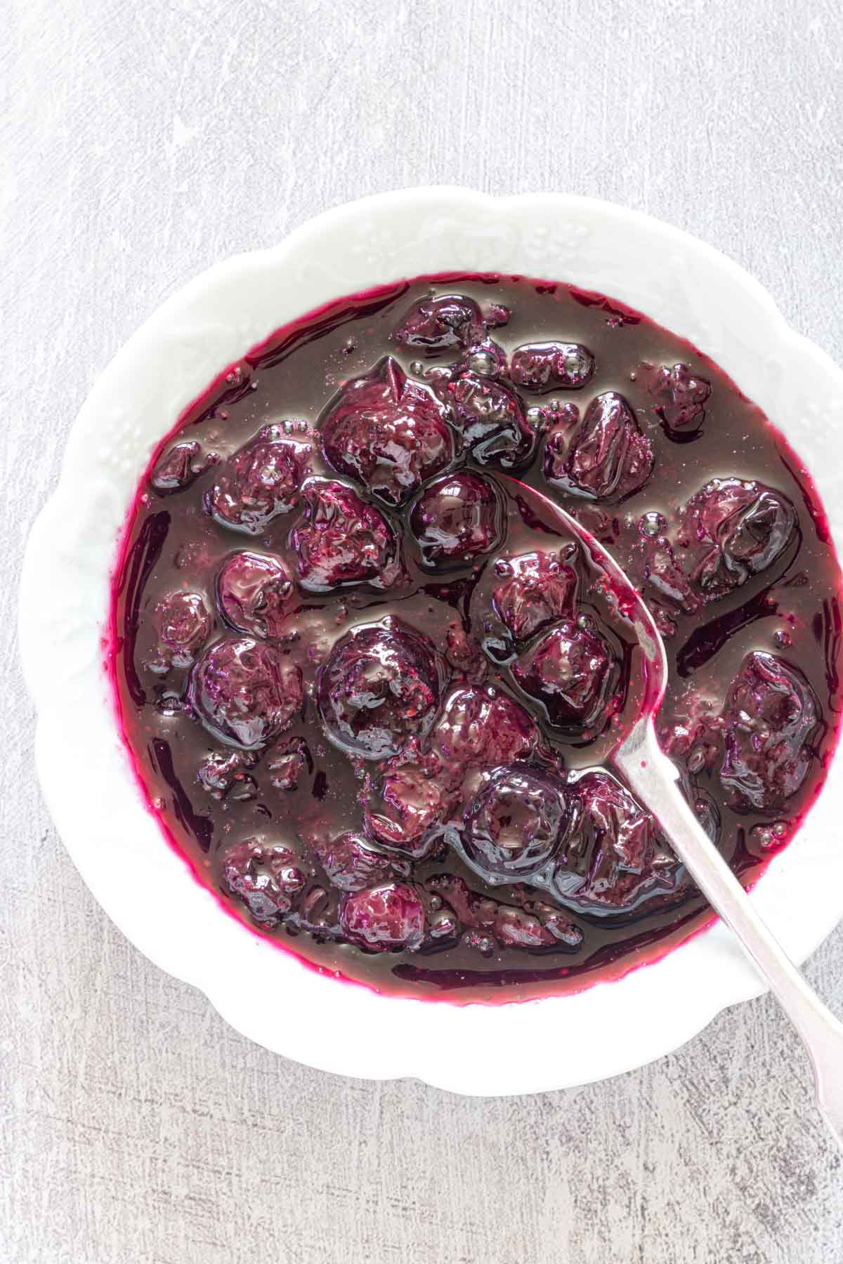 Close up of Instant pot blueberry compote in a bowl with a spoon stuck in