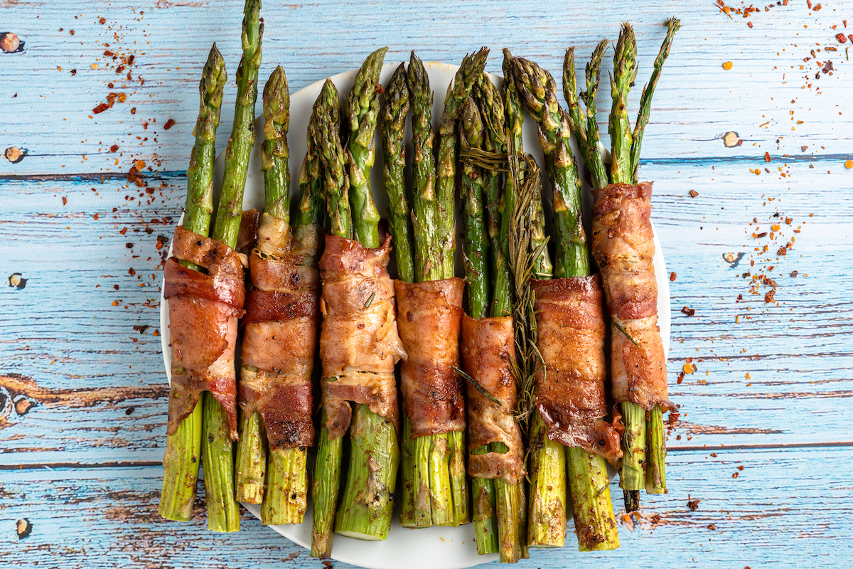 the finished bacon wrapped asparagus served on a white plate