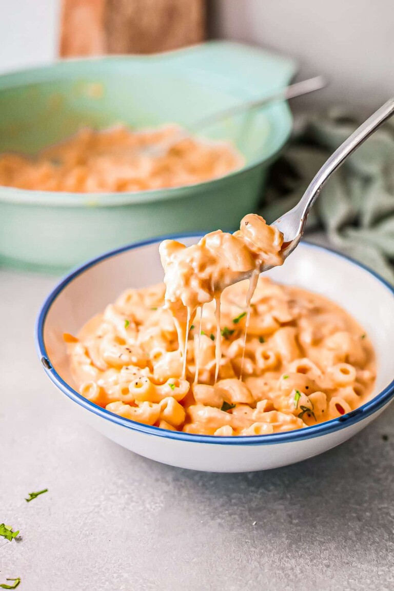 Buffalo chicken mac and cheese in a white bowl, with a fork scooping up a portion.
