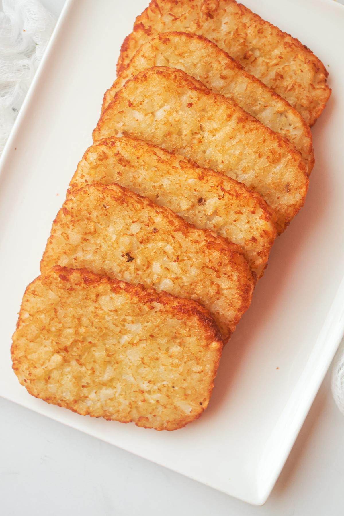 cooked frozen hash browns in oven stacked on a white serving tray