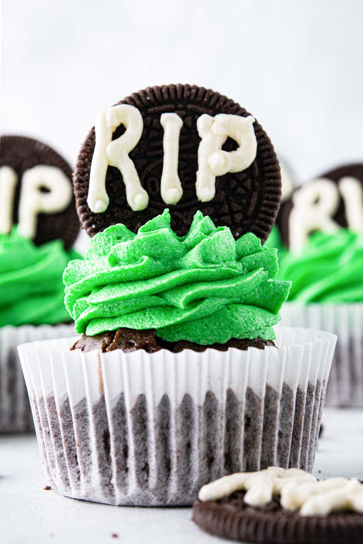 halloween cupcakes decorated with green frosting and a cookie gravestone