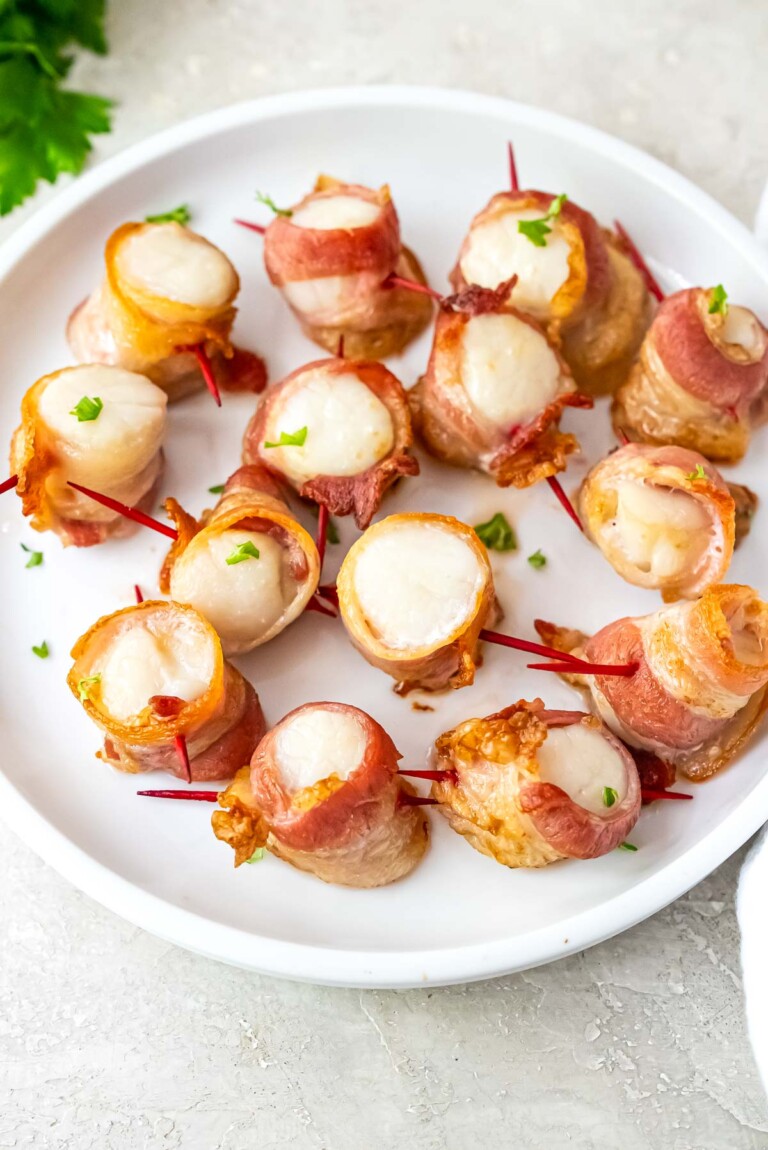the finished air fryer bacon wrapped scallops served on a white plate