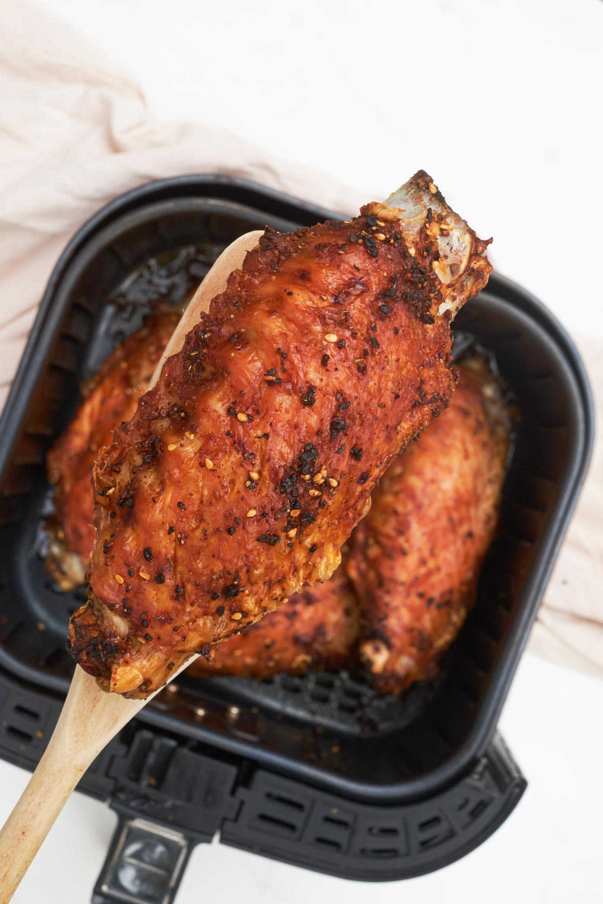 one cooked turkey wing being removed from the air fryer