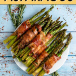 bacon wrapped asparagus on a plate surrounded by rosemary sprigs