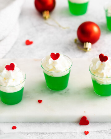 the completed grinch jello shots on a tray with red and green decorations