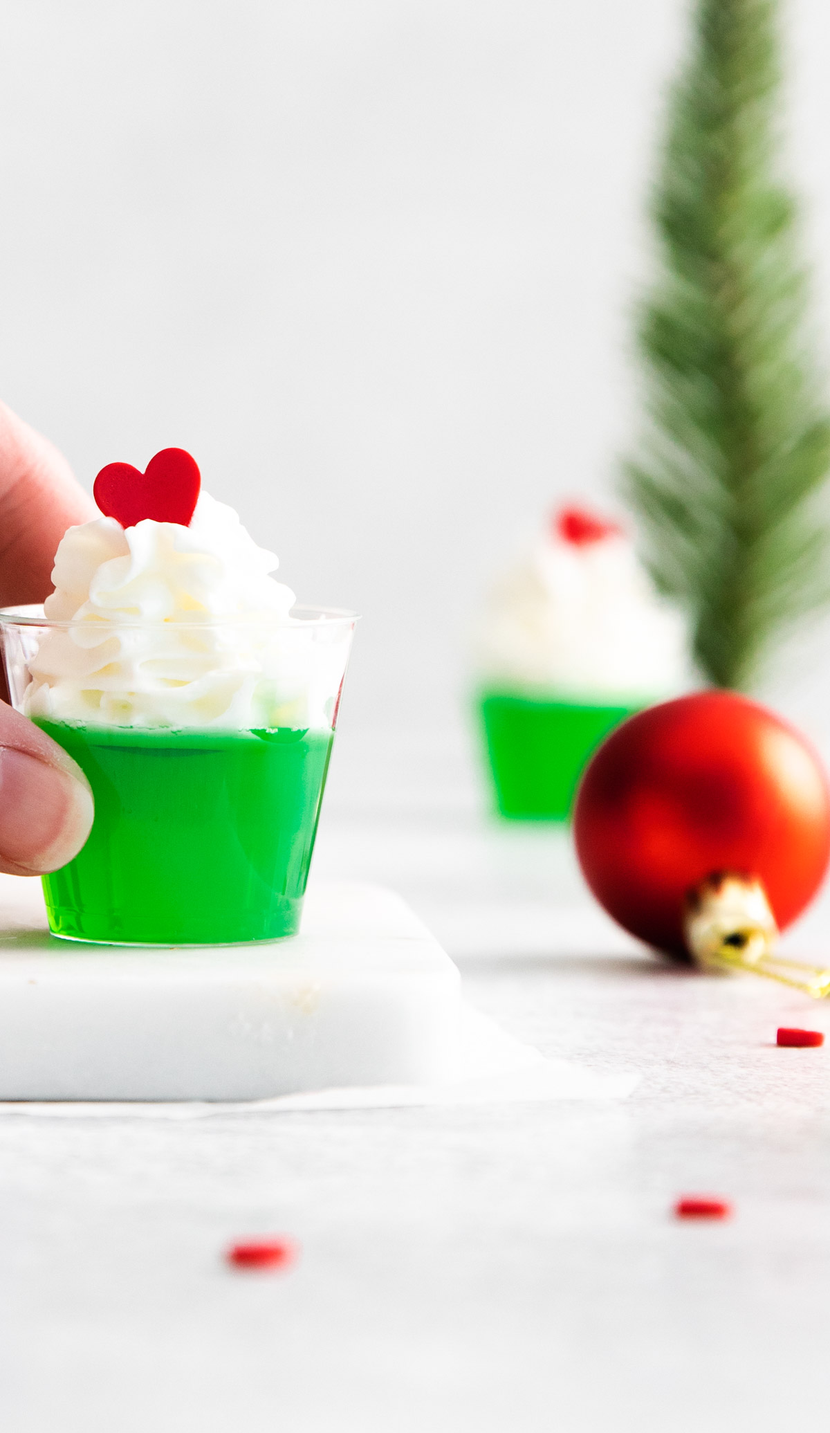 a hand picking up one of the grinch jello shots