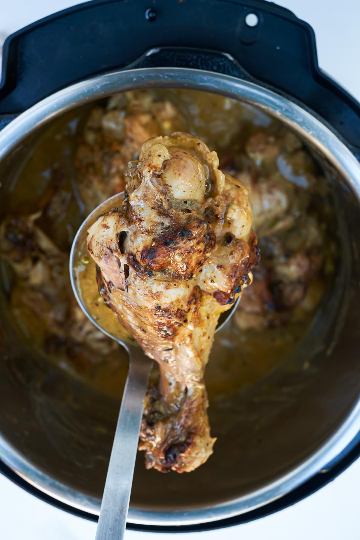 a serving spoon removing one of the cooked turkey wings from the instant pot insert