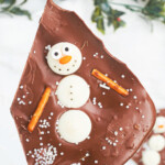 A piece of chocolate bark with a candy snowman in it.