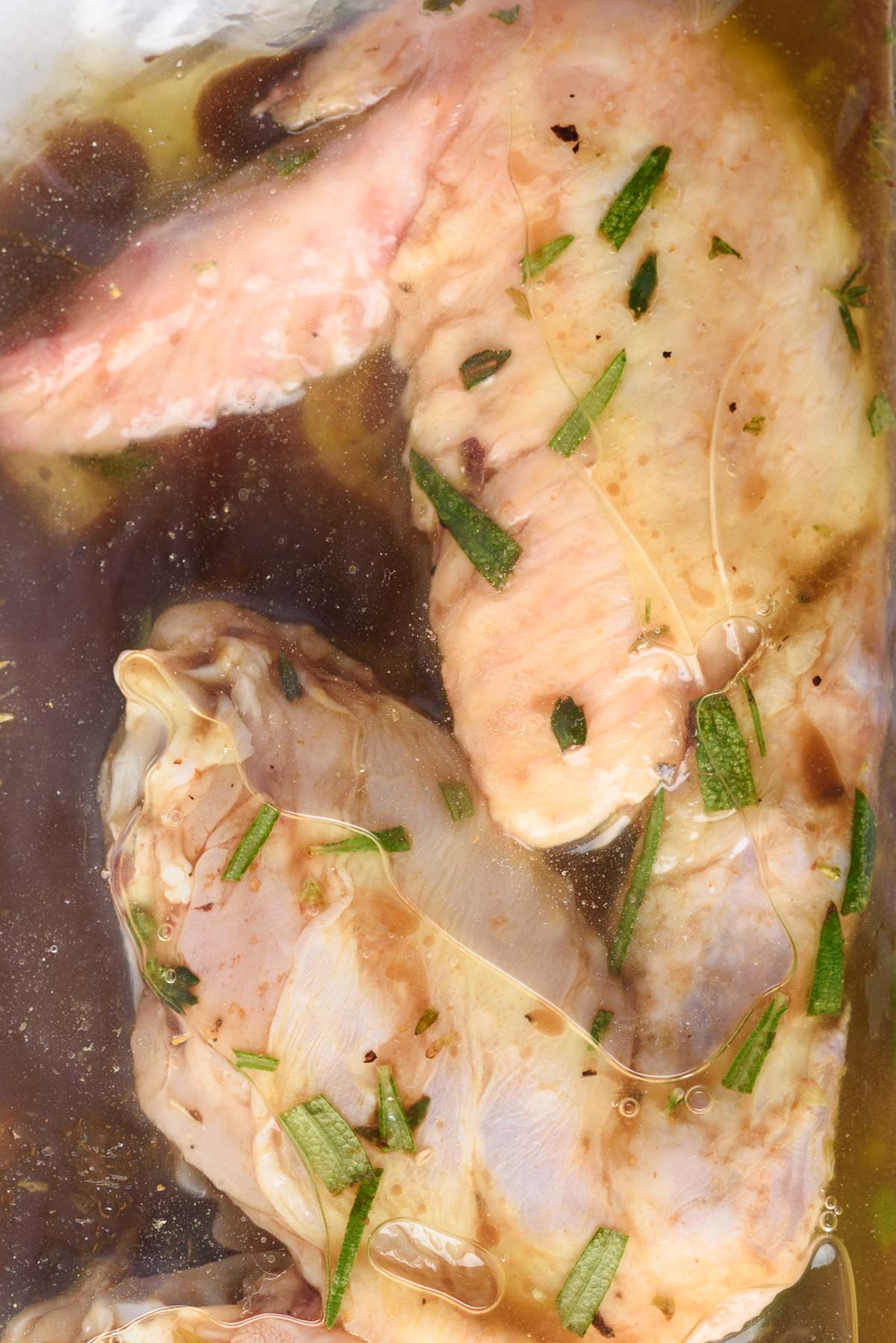 close up view of the marinade and two chicken wings in a ziptop bag