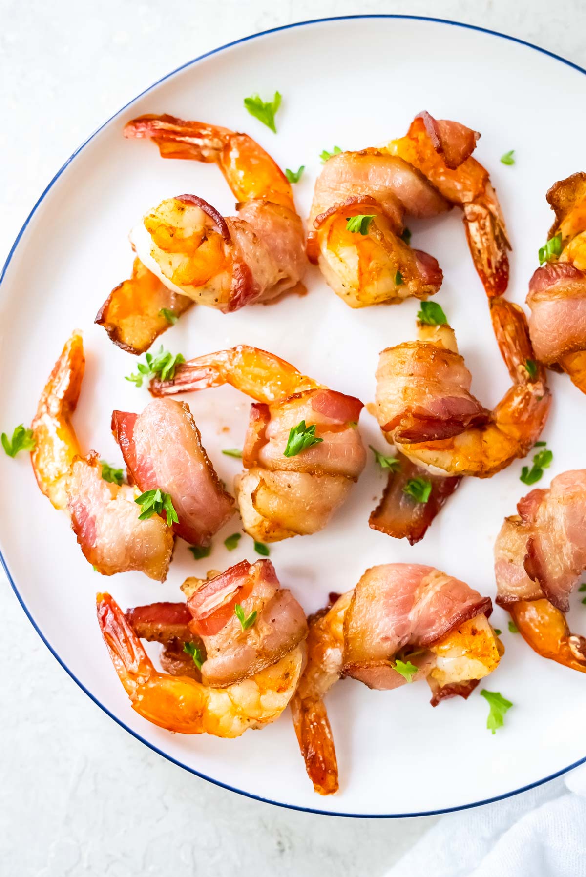 top down view of bacon wrapped shrimp air fryer served on a white plate