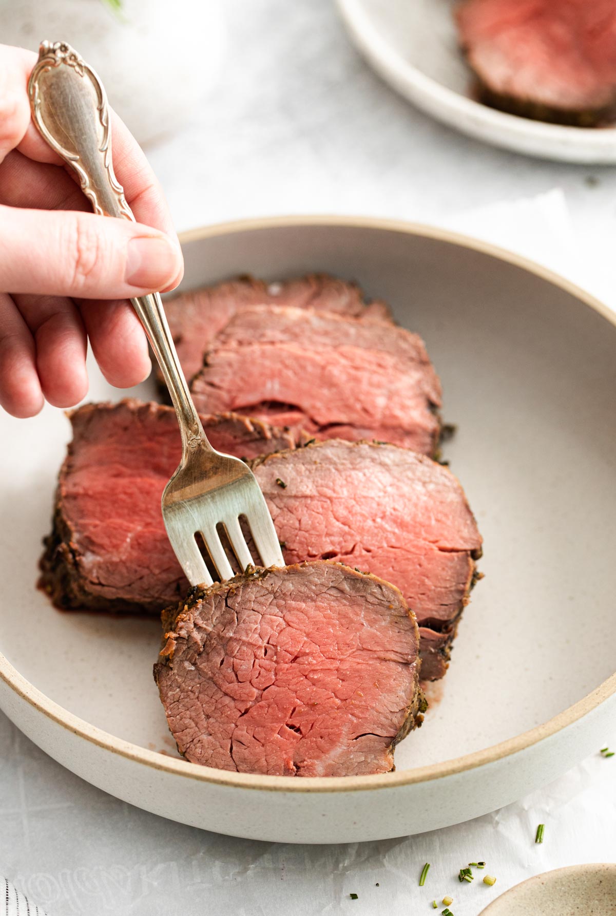 a fork removing one slice of beef tenderloin air fryer from a plate
